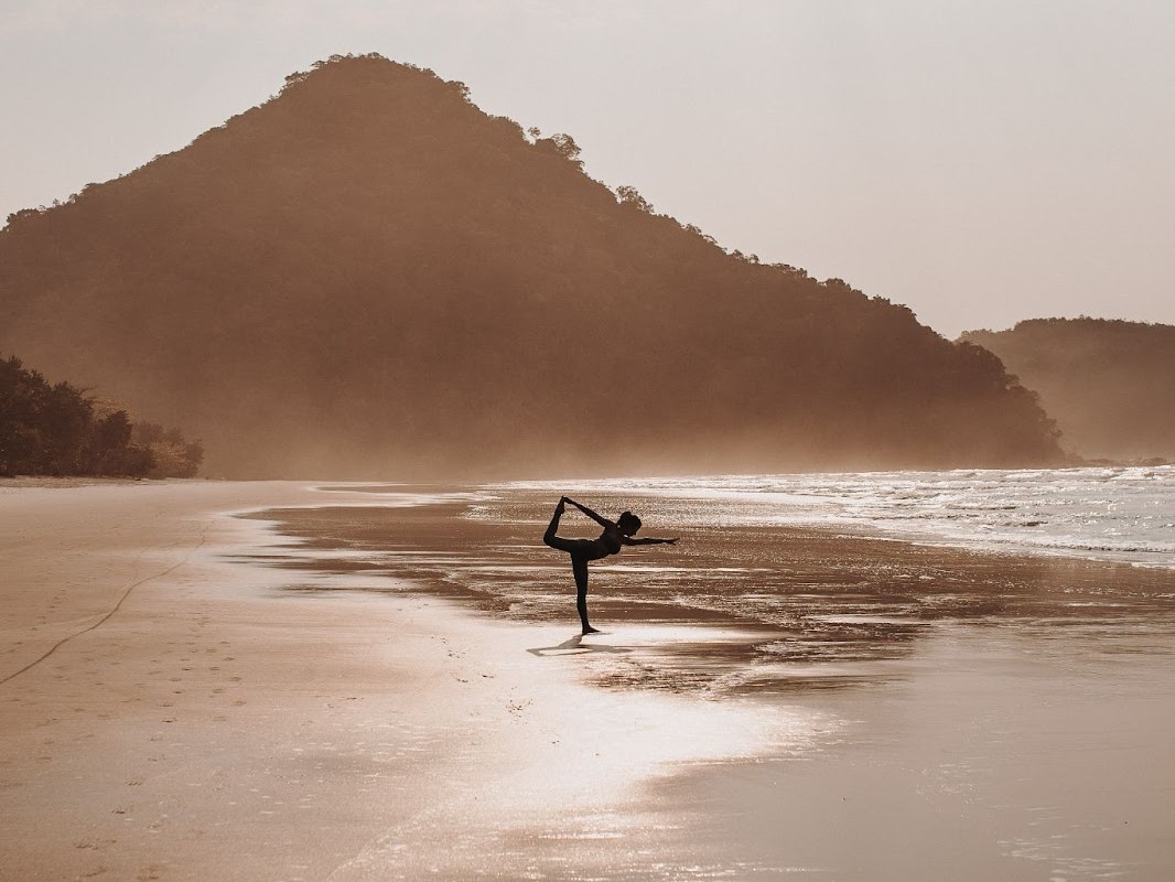 Persona haciendo yoga en la playa.